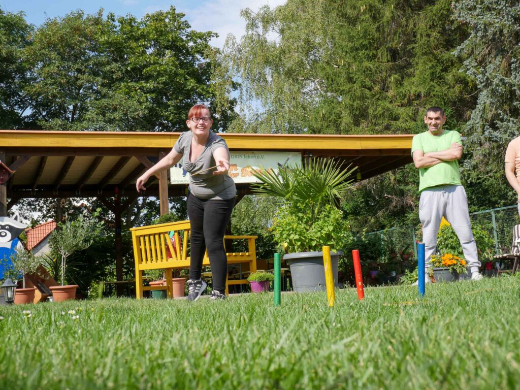 Frau spielt Ringe werfen im Garten der Sinne