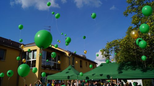 Menschen lassen grüne Luftballons vor dem Stadtteilzentrum Kaulsdorf steigen