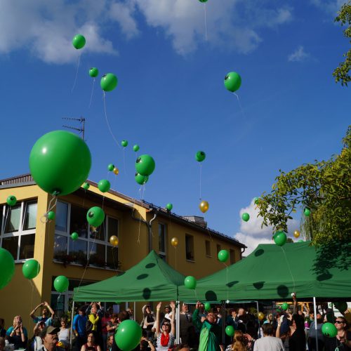 Menschen lassen grüne Luftballons vor dem Stadtteilzentrum Kaulsdorf steigen