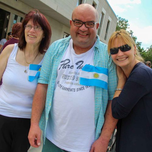 3 Personen beim Tischkicker-Event. 2 Frauen und 1 Mann bilden zusammen das Team Argentinien. Sie tragen die Landesflagge