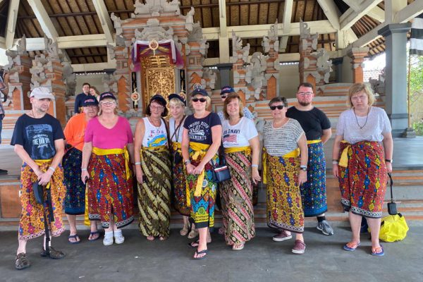 Betreutes Reise nach Bali: Gruppenfoto in einem Tempel. Alle tragen traditonelle Röcke