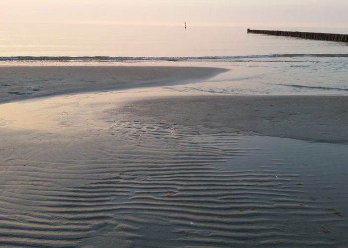 Zingst. Ein leicht überfluteter Strand im Abendlicht